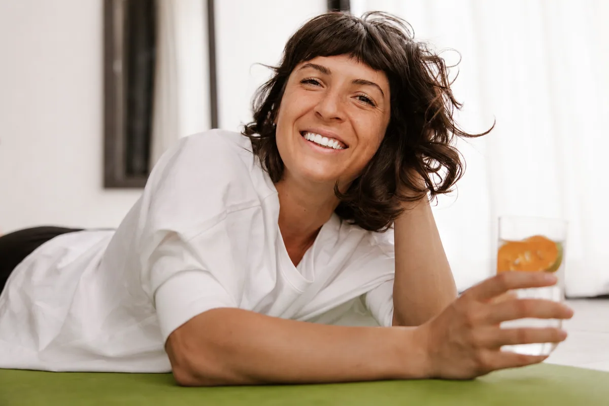 Mujer disfrutando un vaso de agua con naranja